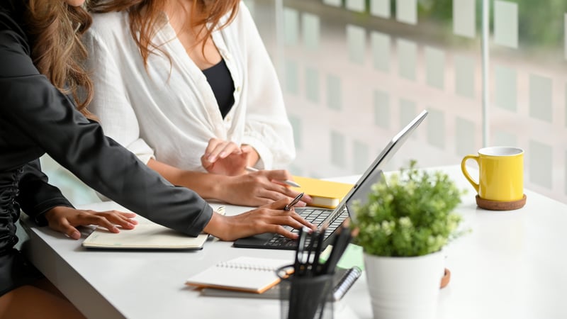 Cropped photo of two women working at a laptop in a business office